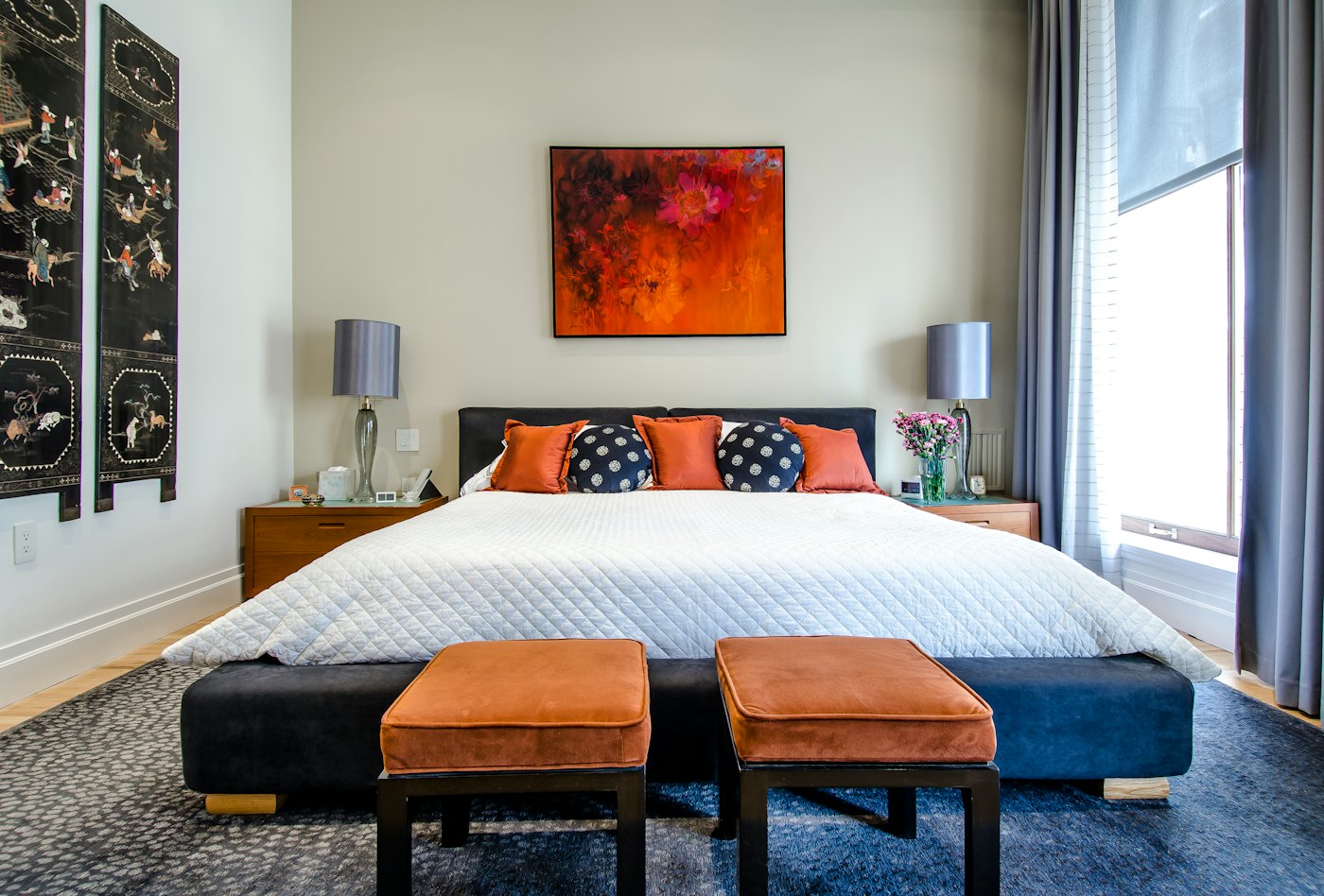 Bedroom with orange upholstered ottomans at the foot of the bed