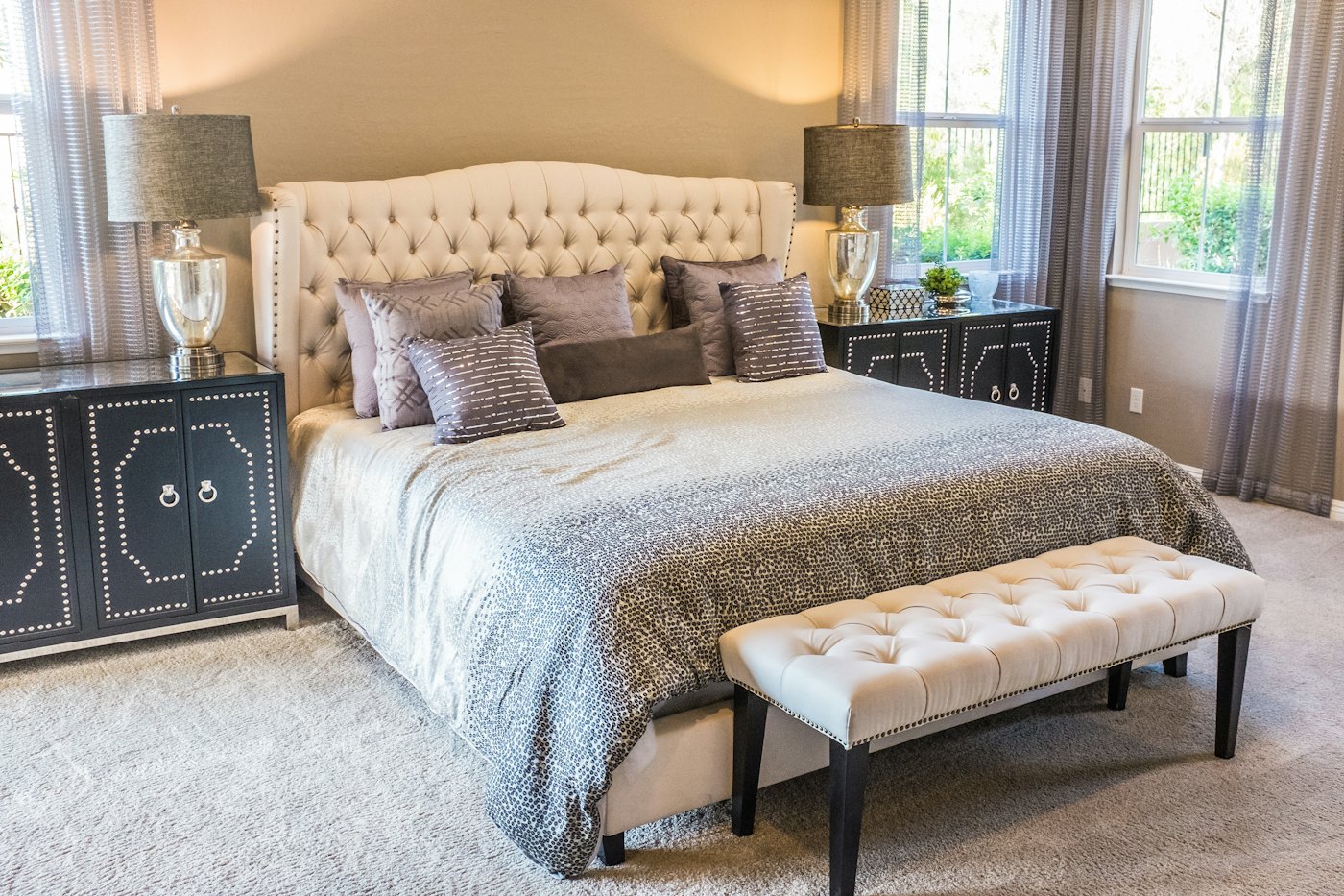 Classic bedroom with a tufted headboard, bench and dark side cabinets