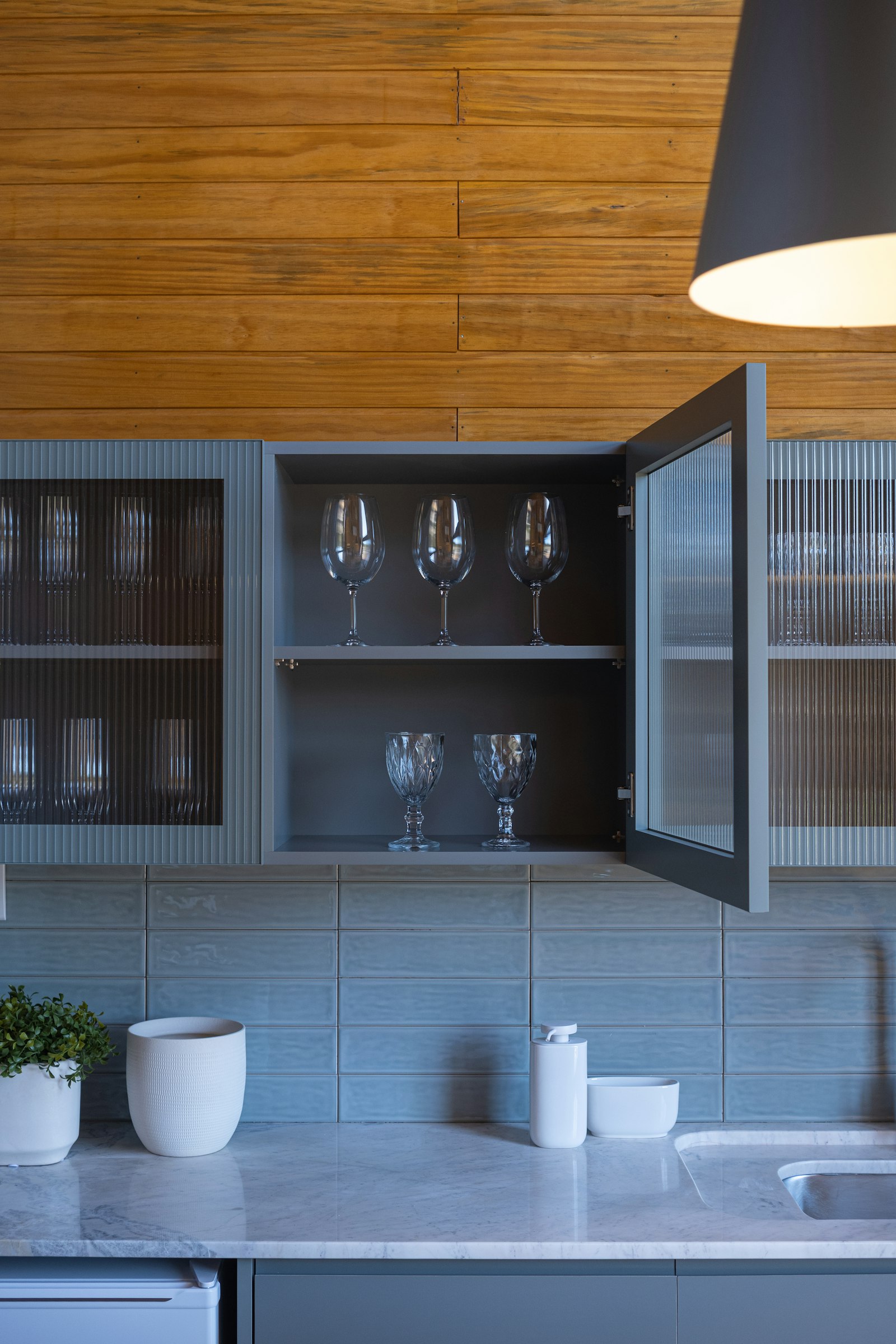 Fluted-glass display cabinets for glassware above a marble counter