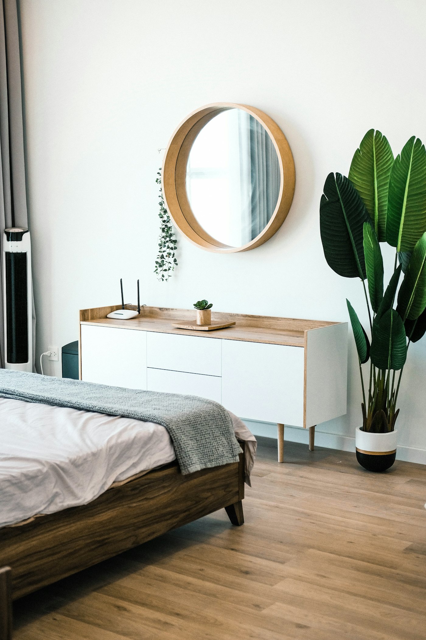 White sideboard with an oak top and a round mirror