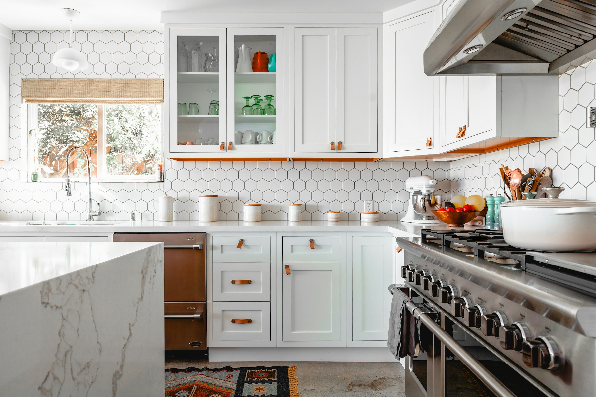 White shaker kitchen with a waterfall marble island and hexagonal tile backsplash