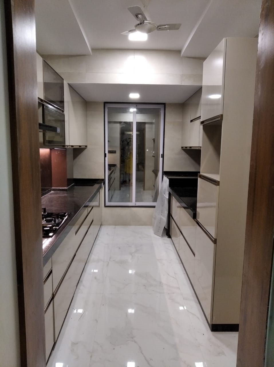 Parallel kitchen in beige high-gloss laminate with dark granite counters