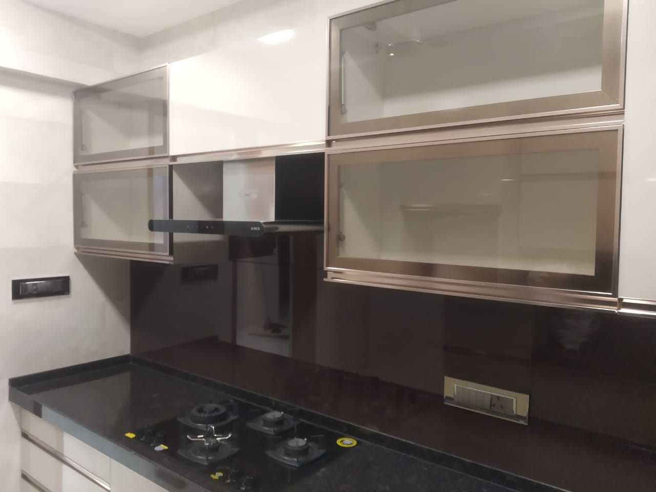 Kitchen with glass wall units and a dark granite counter