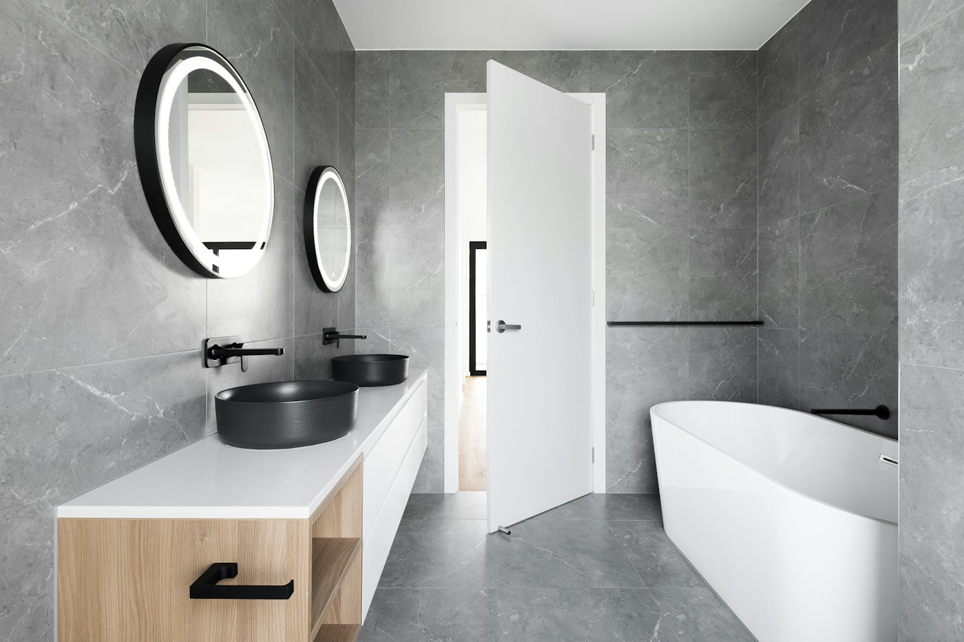Stone-grey bathroom with a round backlit mirror and timber vanity