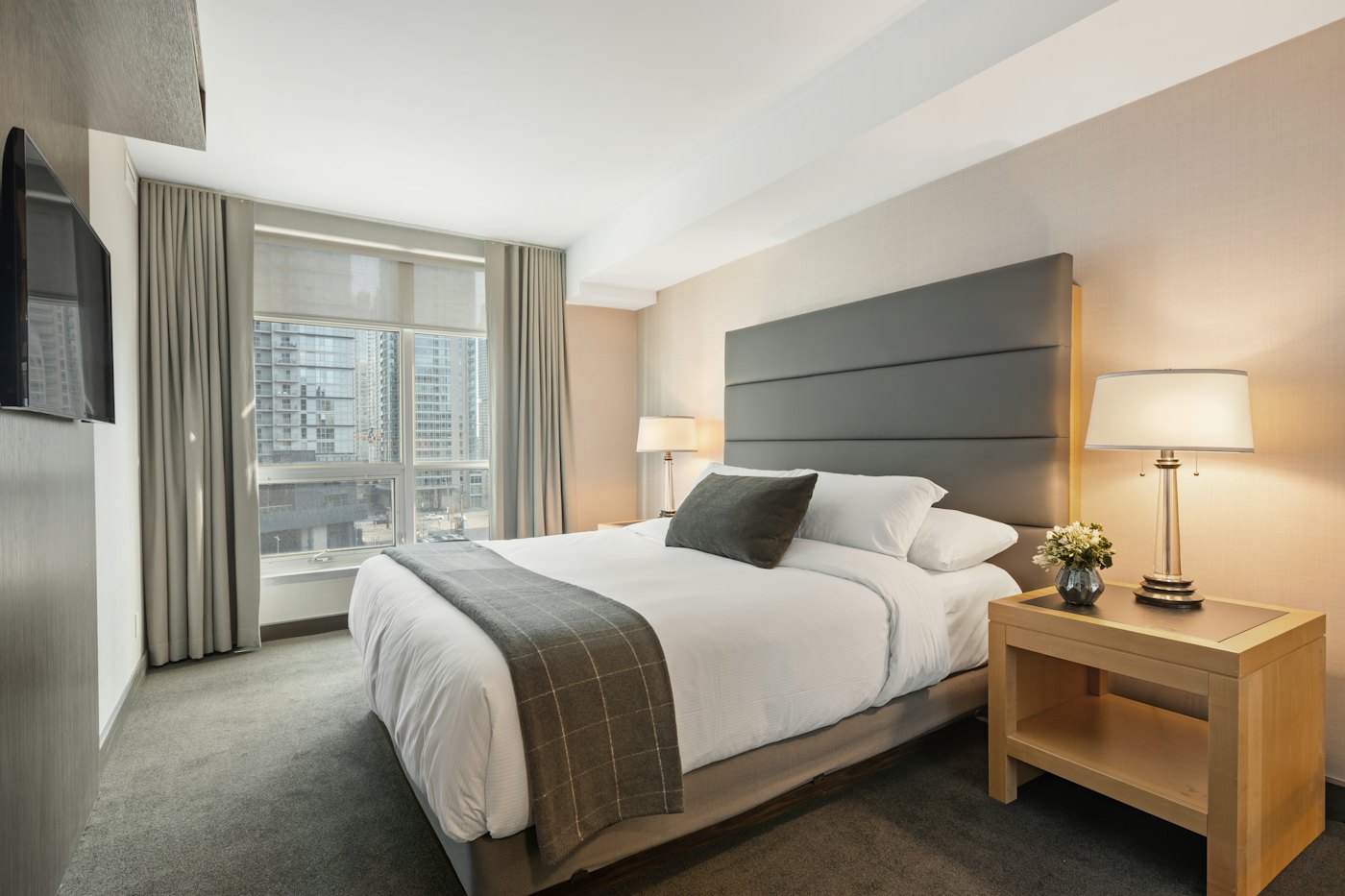 Bedroom with a grey upholstered headboard and wooden side tables