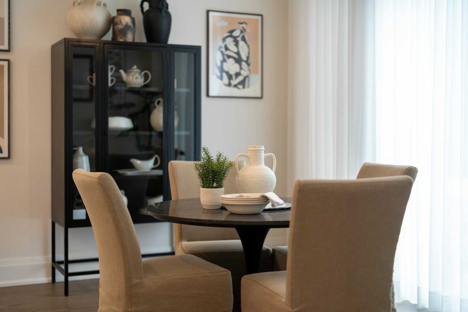 Black-framed glass crockery cabinet beside a round dining table