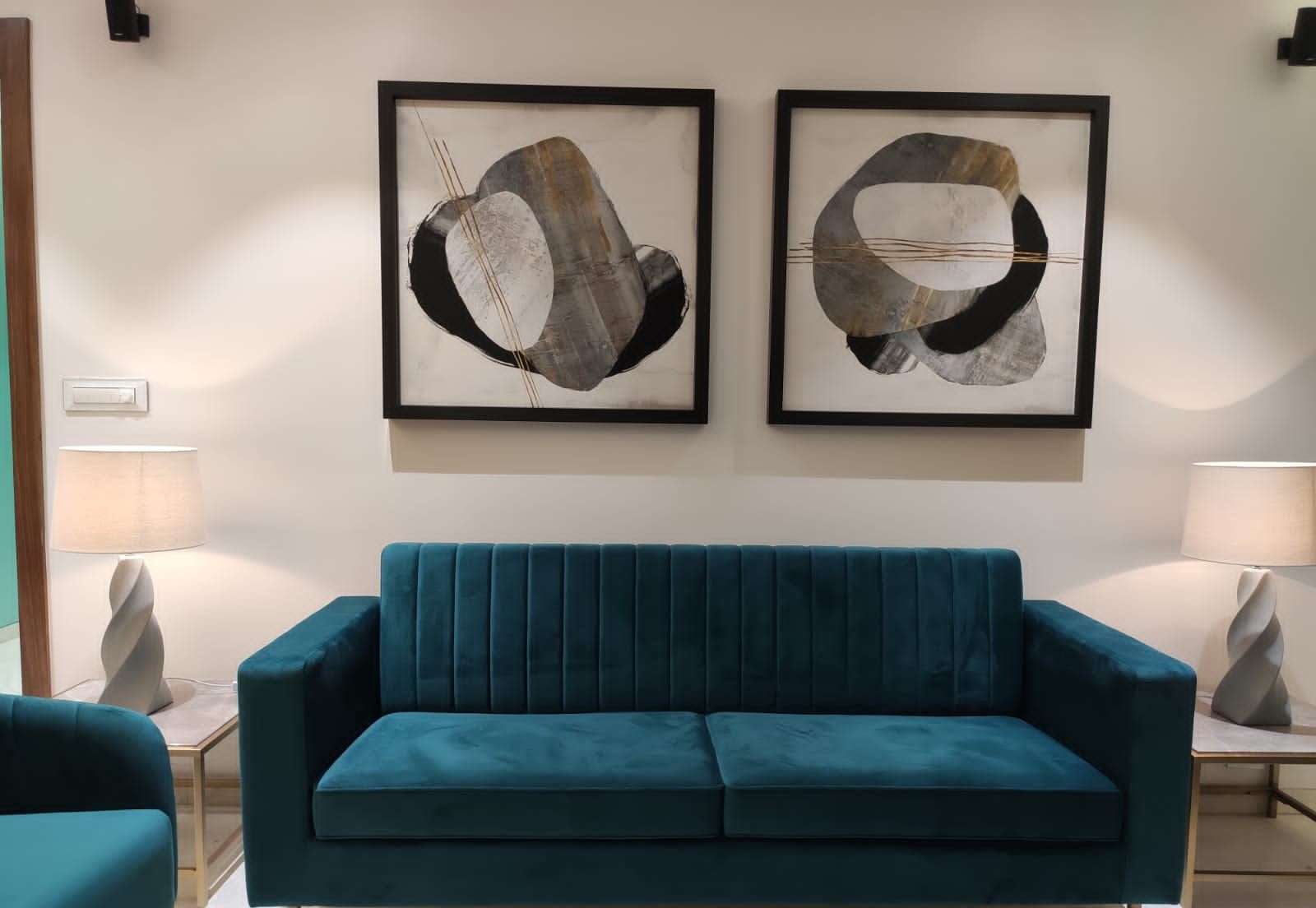 Teal velvet sofa beneath framed artwork